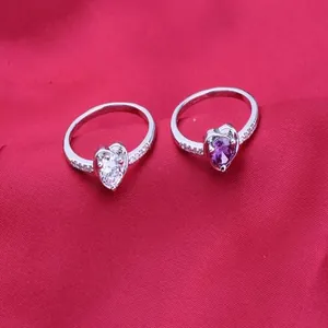 Close-up detail of two heart-shaped zircon rings in silver with white and purple stones