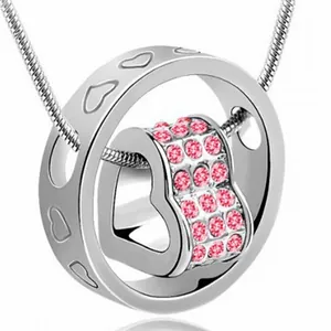 Close-up detail of a silver heart necklace with pink crystals and a rotating pendant