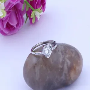 Close-up detail of silver heart-shaped zircon ring on natural stone