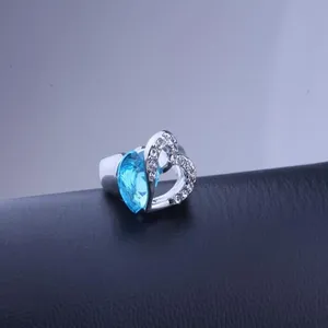 Detailed shot of a silver heart-shaped ring with a sparkling blue crystal gemstone.