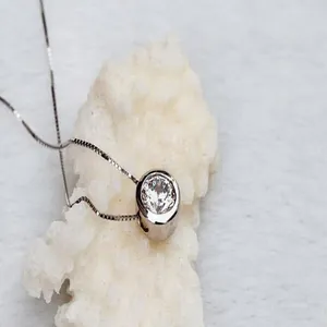 Macro detail of a round silver necklace featuring a sparkling AAA cubic zirconia stone