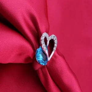 Close-up of Titanic Heart of the Ocean ring with blue crystal on red satin fabric.