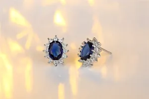Macro close-up of classic oval sapphire halo stud earrings in brilliant silver tone