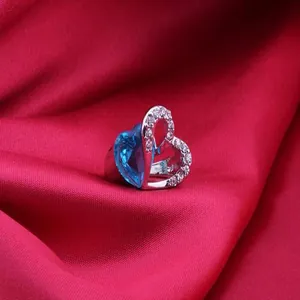 Close-up of Titanic-style silver ring with a blue heart-shaped crystal on red fabric
