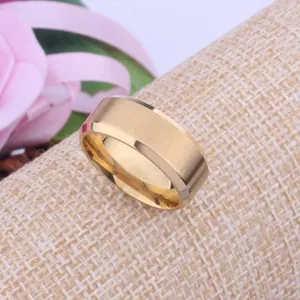 Detail view of gold-plated brushed metal ring with polished beveled edges on textured background