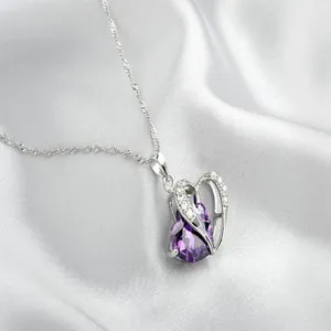 Macro view of a heart-shaped pendant with a teardrop purple zircon in a silver setting.