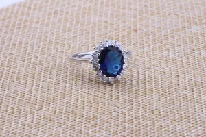 Detailed macro view of elegant oval blue sapphire ring with sparkling zircon halo setting