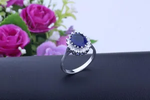 Close-up of a royal style oval blue sapphire ring with sparkling halo zircon accents