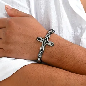 Detail of hip-hop stainless steel cross bracelet on wrist, silver and black finish.
