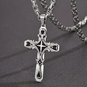 Close-up detail of a gothic stainless steel cross pendant with black inlay on a chain.
