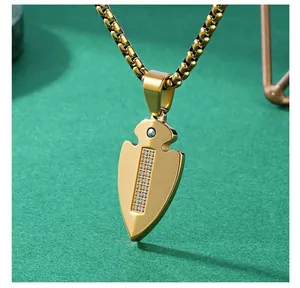 Gold-plated arrowhead pendant necklace with sparkling CZ stones on textured green background