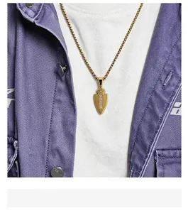 Close-up of a gold spearhead pendant with inlaid rhinestones on a street-style model