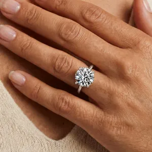 Close-up of a brilliant solitaire moissanite ring with four-prong setting on hand