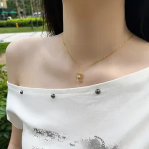 Detailed view of an elegant gold-plated Tibetan prayer wheel necklace on female model