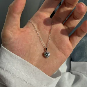 Détail macro d'un collier avec pendentif Moissanite en forme de cœur tenu dans la paume