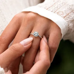 Detailed close-up of a sparkling four-claw moissanite ring worn on a lady's finger