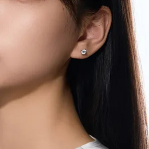 Gros plan d'une boucle d'oreille solitaire ronde étincelante en argent S925 sur l'oreille.