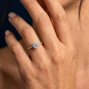 Detailed macro view of a sparkling D color moissanite solitaire ring on a hand