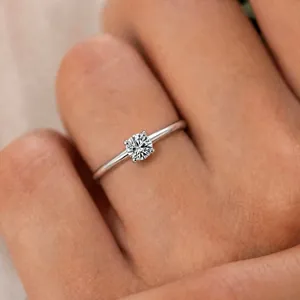 Macro view of a brilliant round moissanite ring set in polished silver four-prong mount