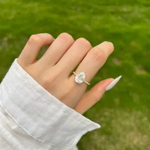 Gros plan d'une élégante bague de fiançailles dorée taille poire portée en plein air