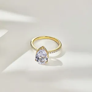 Détail macro d'une bague halo en argent S925 avec pierre en forme de poire dorée.