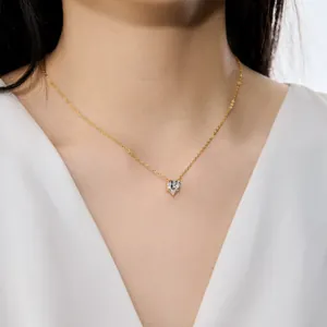 Détail en gros plan d'un élégant collier à pendentif cœur doré porté par un mannequin en haut
