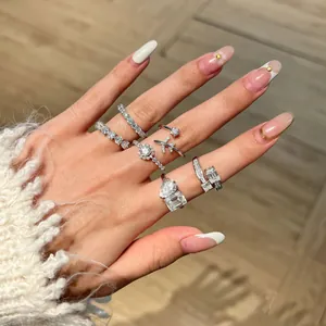 Close-up of S925 silver Moissanite rings with heart and emerald cuts on a hand.
