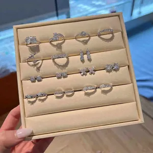Selection of Moissanite jewelry featuring S925 silver rings and earrings on a cream tray.