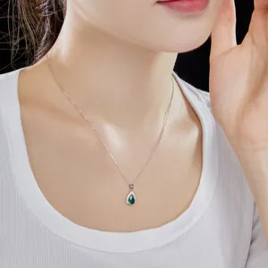 Gros plan d'un collier en argent 925 avec pendentif goutte d'eau verte sur le cou