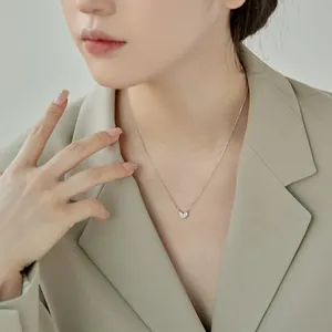 Gros plan d'un collier pendentif cœur en argent sterling S925 porté par un mannequin