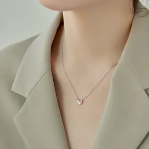 Gros plan d'un collier cœur en argent S925 avec pierres roses et blanches sur modèle