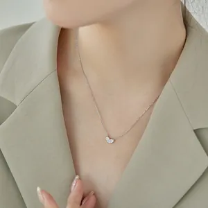 Gros plan d'un délicat collier en argent S925 avec pendentif cœur porté par un mannequin