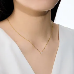 Gros plan d'un délicat collier pendentif en forme de cœur doré porté sur un mannequin