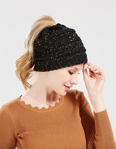 Dettaglio di un berretto in maglia nera con coriandoli e foro per coda di cavallo