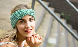Bohemian mint green handmade knitted cross headband worn by a blonde model outdoors