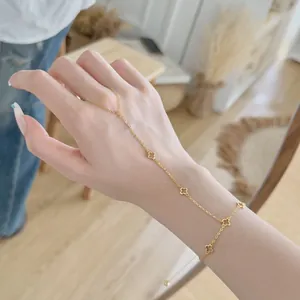 Gros plan d'un bracelet bague doré à motif trèfle porté sur la main pour un style délicat