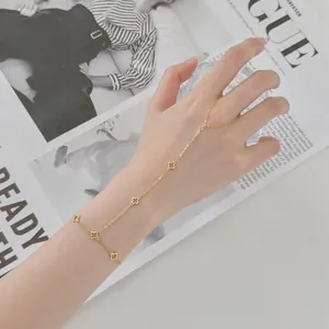 Élégant bracelet de doigt en trèfle à quatre feuilles doré, vue détaillée sur la main.