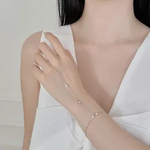 Détail d'une délicate chaîne de main en argent avec tournesol sur une main de femme.