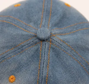 Nahaufnahme einer blauen Denim-Baseballkappe mit orangefarbenen Kontrastnähten.