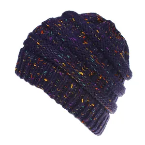 Primo piano di un berretto in maglia viola scuro con dettagli in filato coriandolo vivace.