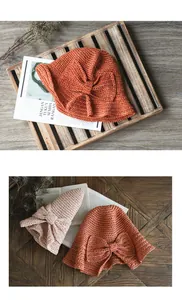 Vue détaillée de chapeaux de paille pliables avec de grands nœuds en orange et en beige.