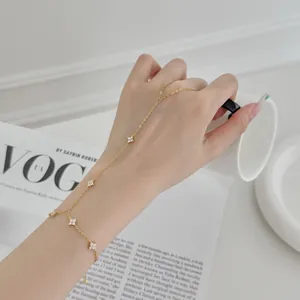 Vue détaillée d'un élégant bracelet de main trèfle à quatre feuilles doré sur main