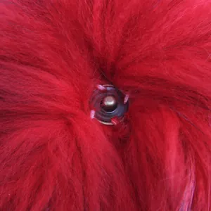 Primer plano de un pompón rojo de piel real de 15 cm con cierre de botón metálico.