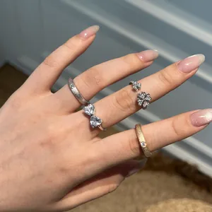 Detailed shot of S925 silver rings with heart and clover accents on a manicured hand