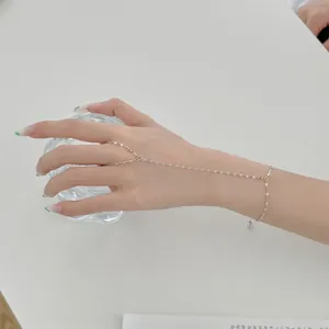 Gros plan d'un bracelet de doigt en argent S925 avec une chaîne fine ondulée.