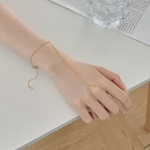 Détail d'un élégant bracelet de doigt en chaîne dorée délicate sur la main d'une femme
