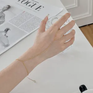 Vue détaillée d'un bracelet de doigt doré délicat porté sur une main.