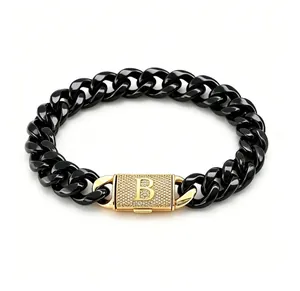 Dettaglio di bracciale a maglia cubana in acciaio nero con chiusura dorata con lettera B