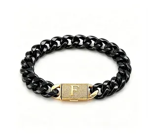 Dettaglio del bracciale a catena in acciaio nero con chiusura dorata con lettera F