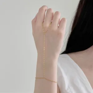 Détail d'un bracelet de doigt délicat en chaîne à cœur doré porté sur une main élégante